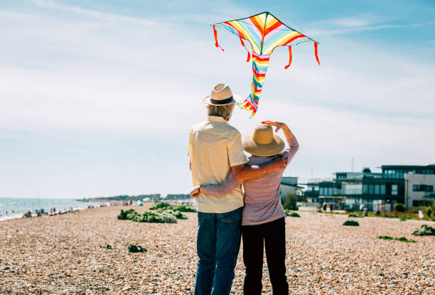 istock Senior couple flying colorful rainbow kite at beach 1321307983