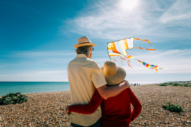 istock Senior couple flying colorful rainbow kite at beach 1321307988