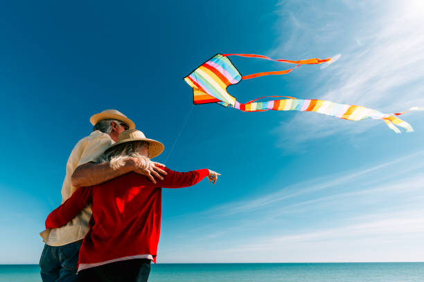 istock Senior couple flying colorful rainbow kite at beach 1321308026