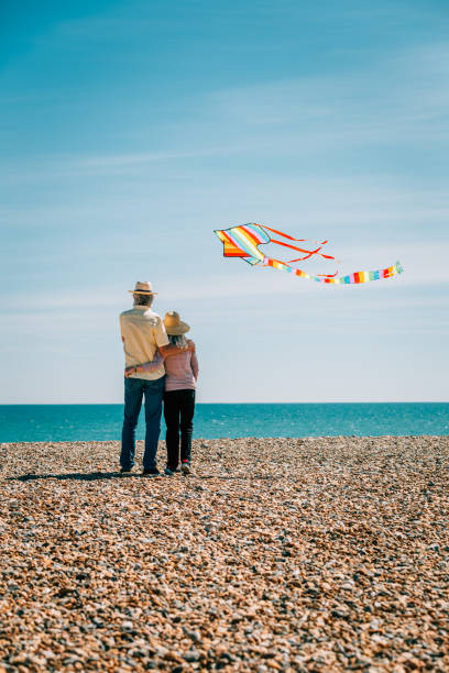 istock Senior couple flying colorful rainbow kite at beach 1321308034