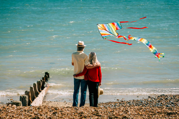 istock Senior couple flying colorful rainbow kite at beach 1321308063