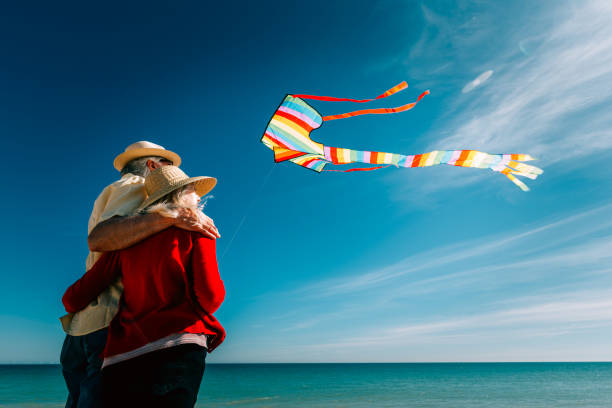 istock Senior couple flying colorful rainbow kite at beach 1321308069
