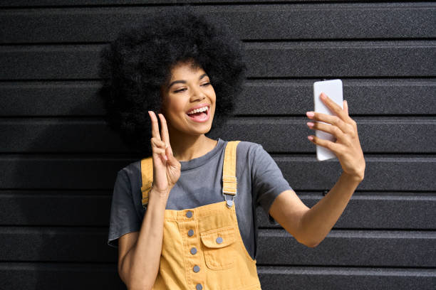 istock Happy stylish young beautiful afro lady taking selfie on black wall background. 1321310131