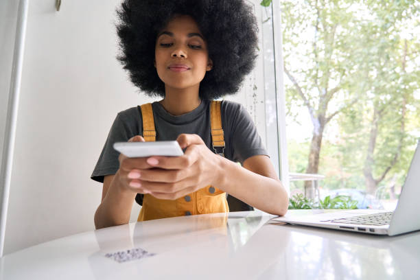 Closeup shot of afro American girl scanning QR code to read menu in cafe. Closeup shot of young black gen z African American girl with afro hair holding cell smart phone scanning qr code to read menu or make payment online in cafe sitting at table indoors. bar code reader stock pictures, royalty-free photos & images