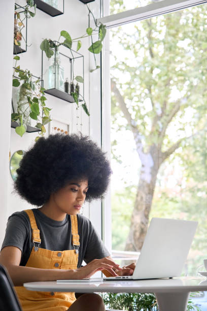 istock Serious black girl sitting in cafe with laptop typing learning online, working. 1321310154