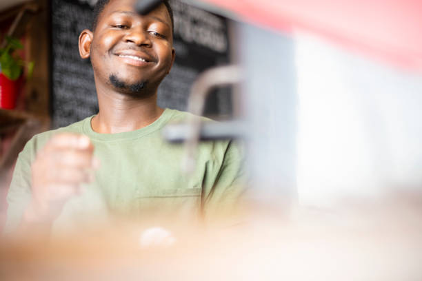 istock Smiling barista operating coffee mashine 1321311263