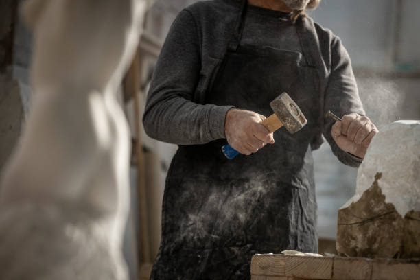 istock Stonemason chiselling a block of stone in workshop 1321311531