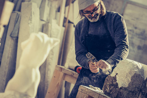 istock Stonemason chiselling a block of stone in workshop 1321311535
