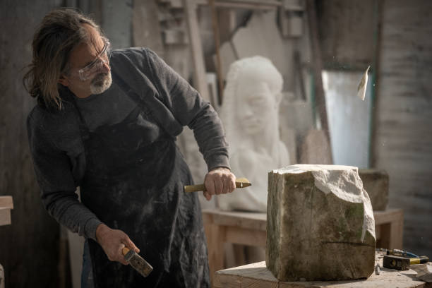 istock Stonemason chiselling a block of stone in workshop 1321311538