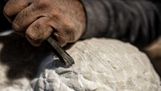 istock Stonemason chiselling surface of white stone 1321311561