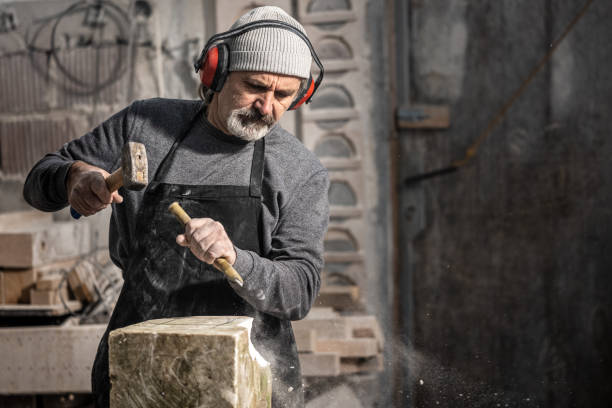 istock Stonemason chiselling a block of stone in workshop 1321311580