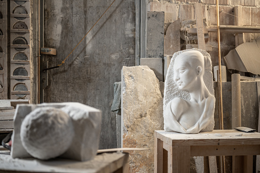 Interior view of stonemason's art studio with bust and pieces of raw stone.