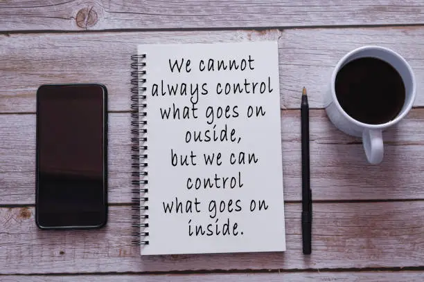 Motivational quote on notepad. We cannot always control what goes on outside, but we can control what goes on inside.