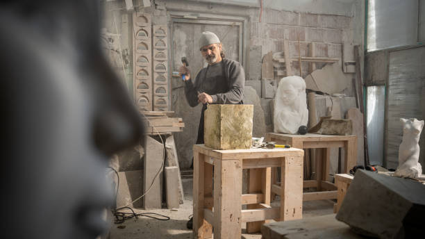 istock Stonemason chiselling a block of stone in workshop 1321312275