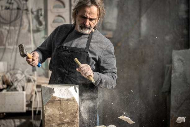 istock Stonemason chiselling a block of stone in workshop 1321312292