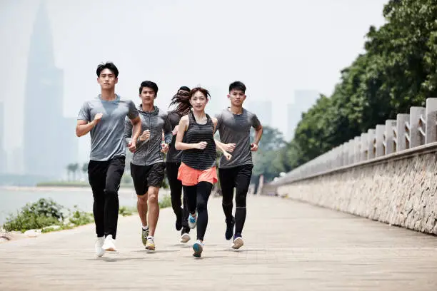 Photo of group of young asian adults running in park