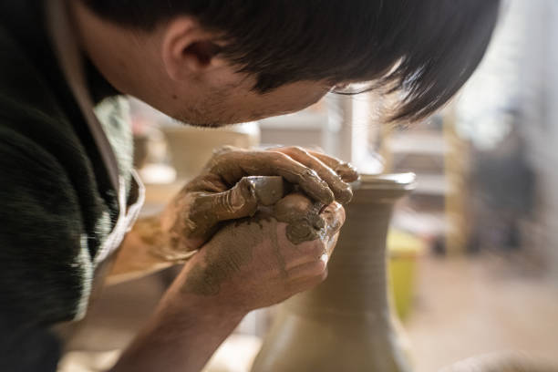 istock Male potter carving top of the vase using hand tool 1321312695