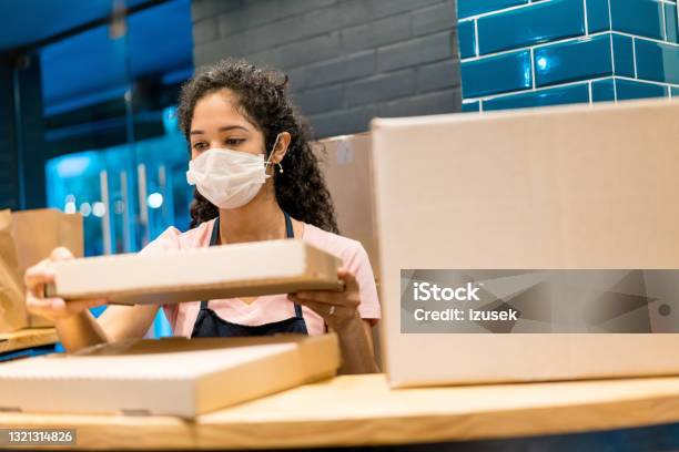 Saleswoman With Pizza Box In Store During Covid19 Stock Photo - Download Image Now - Box - Container, Small Business, UK