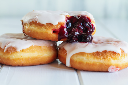 Frosted vanilla donuts filled with blueberry filling. Selective focus with blurred foreground and background.