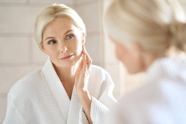 beautiful mid age blond woman standing looking at mirror. skincare. - 4369 imagens e fotografias de stock