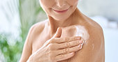 Closeup cut view of mid age woman applying body cream. Antiage skincare concept.