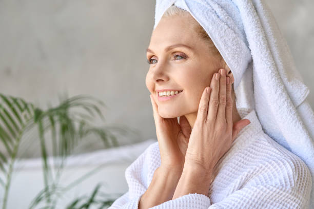 istock Happy smiling mid age woman in bathroom looking at window touching face. 1321321748