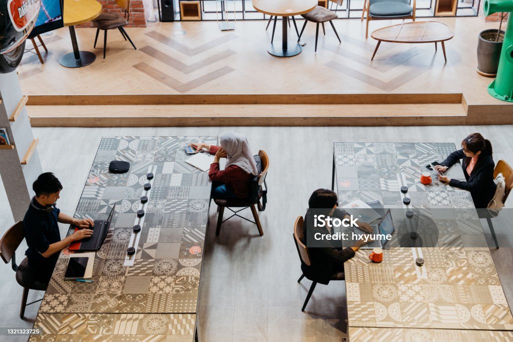 Diverse asian people working in co-working space Multi ethic asian business professionals working in a co-working space. Hot desking in a co-working office. Hot Desking Stock Photo