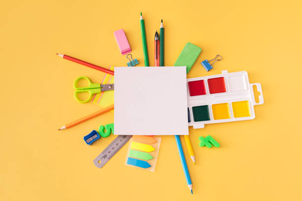istock Blank notebook with school supplies and paints on yellow background 1321323828