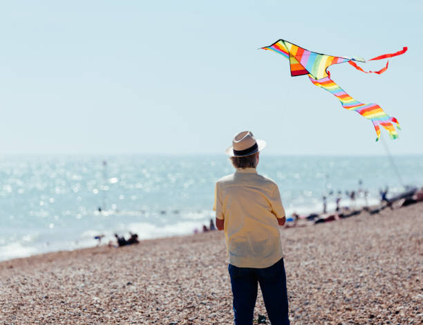istock Senior man flying colorful rainbow kite at beach 1321324807