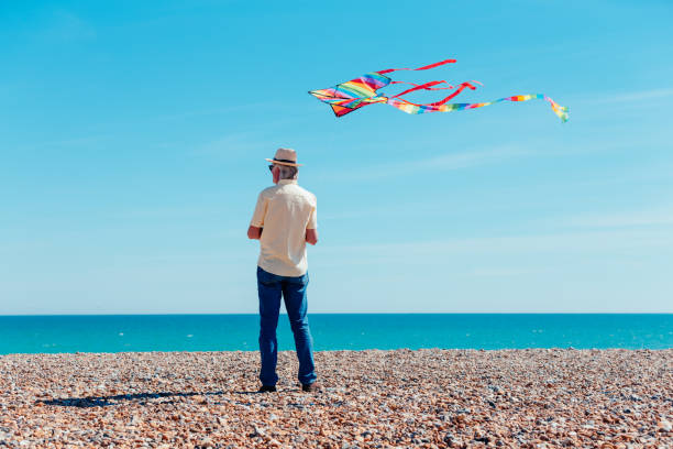 istock Senior man flying colorful rainbow kite at beach 1321324819