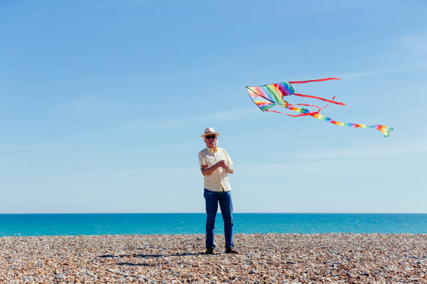 istock Senior man flying colorful rainbow kite at beach 1321324820