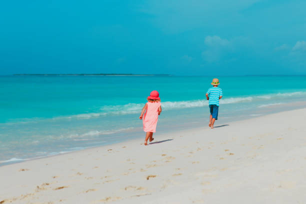 istock happy boy and girl running on beach 1321326359