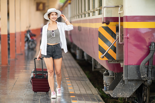 Cheerful Asian woman traveler walking in the train station.