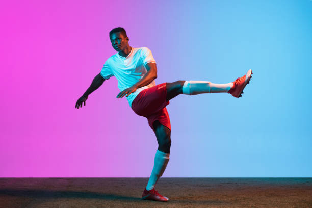 istock One African man, professional soccer football player training isolated on gradient blue pink background in neon light. 1321328021