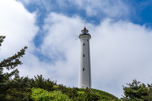 Lighthouse Pontusval Brittany France. Coast area with lighthouse, rocks, sea, waves and beach. Dramatic clouds in the sky.