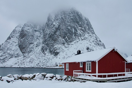 Red rorbu in front of high mountain in Lofoten, Norway