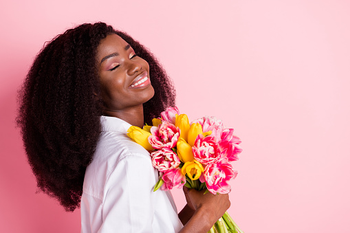 Profile photo of nice optimistic brunette hairdo lady hold flowers wear white shirt isolated on pink color background.