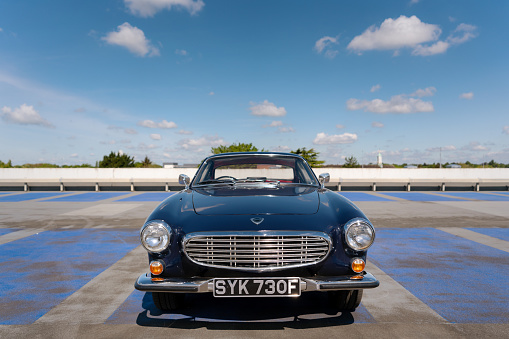 Hertfordshire - May 27, 2021: The sun shines down on a dark blue Volvo 1800S from 1967 in a car park.