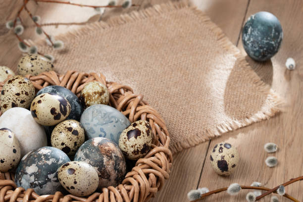 istock Easter composition - Easter eggs painted with natural dyes in a wicker nest on a wooden table, copyspace 1321330967