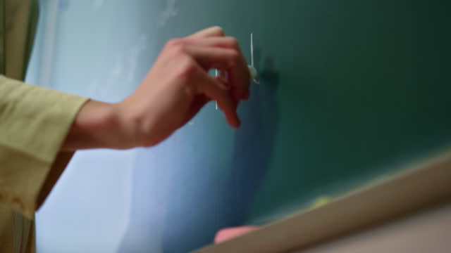 Teacher drawing on blackboard. Schoolteacher hand writing on chalkboard