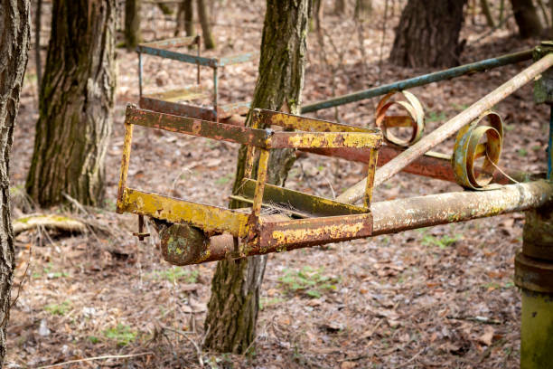 Old broken rusty metal carousel swing on abandoned playground among trees in ghost town Pripyat, Chernobyl Exclusion Zone, Ukraine