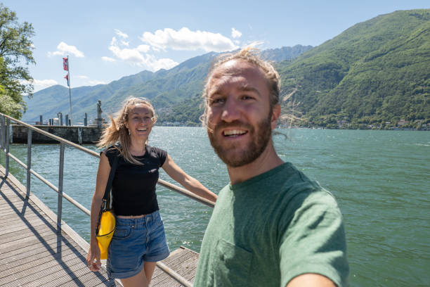 istock Couple walk along lakeside pier in Summer, take selfie 1321331644