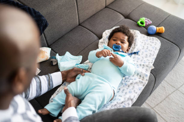 istock Father playing with baby son and changing his clothes at home 1321335360