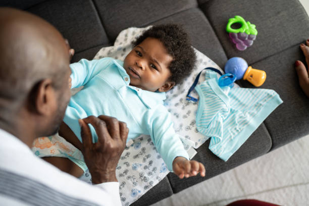 istock Father playing with baby son and changing his clothes at home 1321335366
