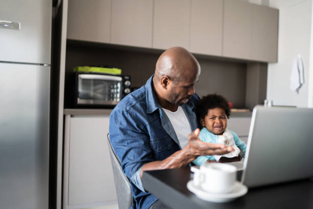 istock Father with crying baby boy while working at home 1321335515