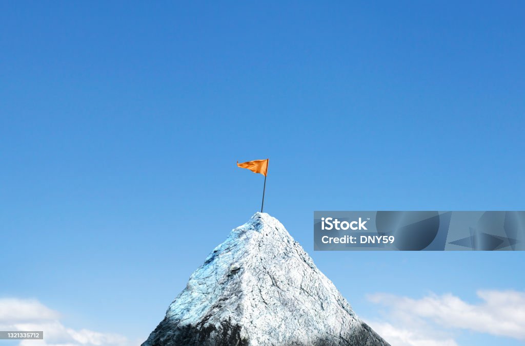 Orange Flag Planted on Top Of Snow Capped Peak An orange flag is planted on top of a snow cap peak. Soft clouds frame the lower portion of the image and a rich blue sky provides ample room for copy or text. Mountain Peak Stock Photo