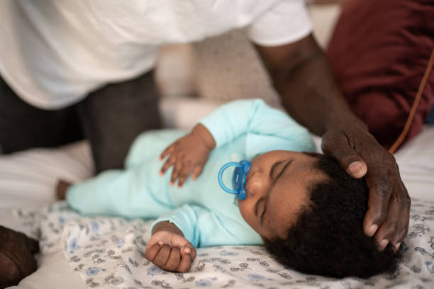 istock Father putting sleeping son on the bed at home 1321335723