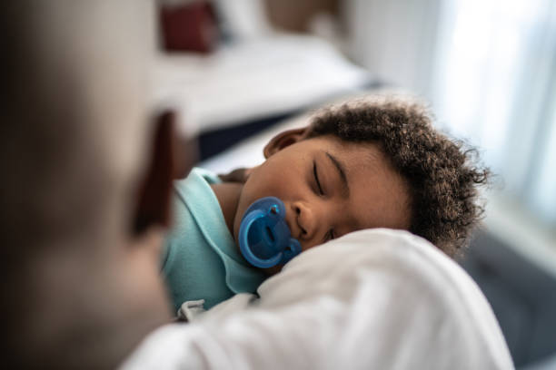 padre che mette il figlio a dormire sulle braccia a casa - sleeping baby foto e immagini stock