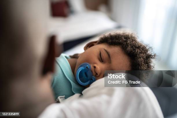 Father Putting Baby Son To Sleep On His Arms At Home Stock Photo - Download Image Now