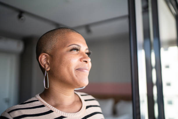 mujer madura contemplando en casa - completely bald fotografías e imágenes de stock